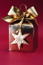 Golden wrapped gift box with bow against red background