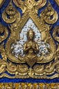 Golden Yaksha in front of silver and blue mirror tiles