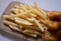 Golden yellow french fries and chicken nuggets on wooden plate. Closed up