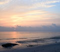 Golden Yellow Lines in Clouds in Morning Sky with Rising Sun at Horizon over Vast Ocean