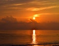 Golden Yellow Shining Sun Rising at Horizon with Reflection in Sea Water with Warm Colors in Clouds in Morning Sky Royalty Free Stock Photo