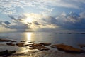 Golden Yellow Sun with Bright Sunlight rising from behind Clouds with Reflection in Sea Water - Morning Sky at Beach