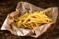 Golden yummy deep French fries on kraft baking sheet paper and serving tray to eat, lifestyle.