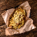 Golden yummy deep French fries on kraft baking sheet paper and serving tray to eat, lifestyle.