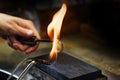 Goldsmith hands glow a golden ring in a gas flame, close up with