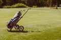 Golf bag trolley with clubs on green, copy space Royalty Free Stock Photo