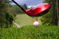 Golf ball and blurred golf club in the beautiful golf course in Thailand. Collection of golf equipment resting on green grass with Royalty Free Stock Photo