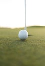 Golf ball close to cup hole on putting green