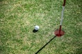 Golf ball close to hole on green grass field. close to goal target concept with golf sport caption Royalty Free Stock Photo