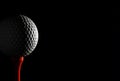 Dramatic close-up of a golf ball on a red tee against a stark black background. Royalty Free Stock Photo