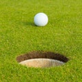 Golf ball in front of the hole, focus on the hole Royalty Free Stock Photo