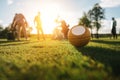 Golf ball on grass and silhouettes of golfers playing behind Royalty Free Stock Photo