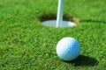 Golf ball green grass in front of hole Royalty Free Stock Photo