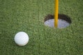 Golf ball on green grass in front of hole Royalty Free Stock Photo