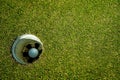 Golf ball in hole on a green lawn in a beautiful golf course with morning sunshine Royalty Free Stock Photo