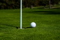 Golf ball on lip of cup on grass background. Golf hole. Royalty Free Stock Photo