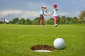 Golf, ball lying on the green next to hole, in the two young golfers Royalty Free Stock Photo