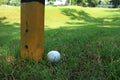 Golf Ball beside Marker Pole