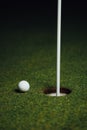 Golf ball nearby hole with pin flag, green grass background Royalty Free Stock Photo