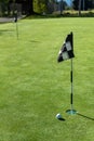 Golf ball on practice putting green next to hole and flag, sunny morning Royalty Free Stock Photo