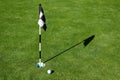 Golf ball on practice putting green next to hole and flag, sunny morning Royalty Free Stock Photo