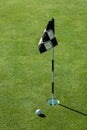 Golf ball on practice putting green next to hole and flag, sunny morning Royalty Free Stock Photo