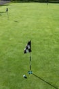 Golf ball on practice putting green next to hole and flag, sunny morning Royalty Free Stock Photo