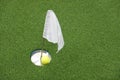 Golf ball on practice putting green next to hole and white flag. Royalty Free Stock Photo