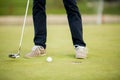 Golf ball, putter and boy's legs on green Royalty Free Stock Photo