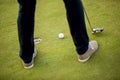 Golf ball, putter and boy's legs on green Royalty Free Stock Photo