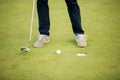 Golf ball, putter and boy's legs on green Royalty Free Stock Photo