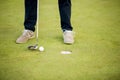 Golf ball, putter and boy's legs on green Royalty Free Stock Photo