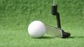 Golf ball and putter on green grass