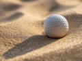 A golf ball resting in a sandy bunker with detailed texture and warm sunlight casting a long shadow on the fine granules of sand Royalty Free Stock Photo