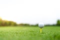 Golf ball on tee with clipping path, blur bokeh golf course background with copy space on sky, golden twilight sunset effect Royalty Free Stock Photo