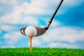 Golf ball on tee and golf club on grass on blue sky and cloud background Royalty Free Stock Photo