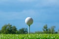 Golf ball on tee on golf course on blue sky Royalty Free Stock Photo