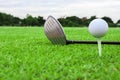 Golf ball on a tee and driver in green grass course Royalty Free Stock Photo