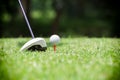 Golf ball on tee in front of golf driver on a gold course grass green field,the driver positioned ready to hit the golf ball Royalty Free Stock Photo