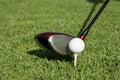 Golf ball on tee in front of a driver Royalty Free Stock Photo