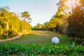 Golf ball on tee at green lawn in a beautiful golf course with morning sunshine.Ready for golf in the first short.Sports that Royalty Free Stock Photo