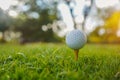 Golf ball is on tee at green lawn in a beautiful golf course with morning sunshine.Ready for golf in the first short Royalty Free Stock Photo