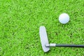 Golf ball on a tee and putter in green grass course Royalty Free Stock Photo