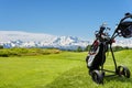 Golf cart with bag and golf clubs at the edge of the fairway of a golf course. In the background the Alps, the Monte Rosa chain, Royalty Free Stock Photo