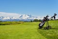 Golf cart with bag and golf clubs at the edge of the fairway of a golf course. In the background the Alps, the Monte Rosa chain, Royalty Free Stock Photo