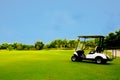 Golf cart car in fairway of golf course with fresh green grass field and cloud sky Royalty Free Stock Photo