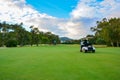 Golf cart on a golf course. Green field and cloudy blue sky. Spring landscape with grass and trees. Royalty Free Stock Photo