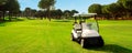 Golf cart in fairway of golf course with green grass field with blue sky and trees Royalty Free Stock Photo