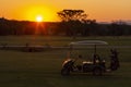 Golf cart on a golf course at dawn and a colorful sunset in the background Royalty Free Stock Photo