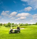 Golf cart on a golf course. Green field and cloudy blue sky Royalty Free Stock Photo